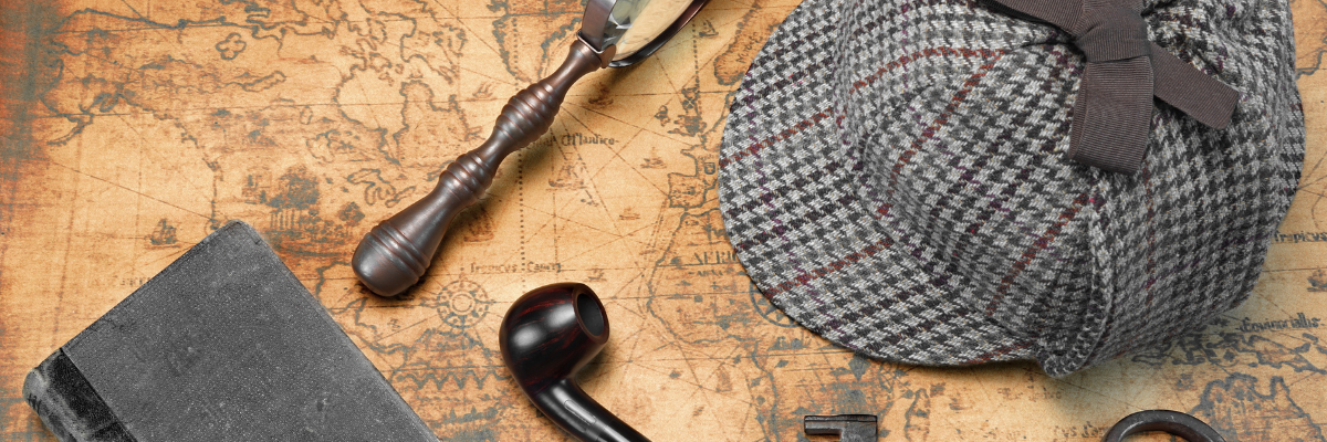 Office Halloween Costume. An old detective hat, magnifying glass, book, and pipe are lying on top of a yellowed map of the world.